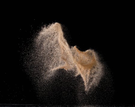 Foto de Explosión de vuelo de arena natural, onda de grano de punto de partícula explota. Nube abstracta vuela. Salpicadura de arena de color marrón lanzando aire. Fondo negro Aislado - Imagen libre de derechos