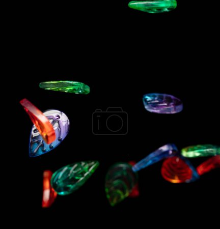Photo for Fashion colorful plastic leaf with beautiful work detail is value. Luxury leaf bead red blue green is fashion trend and fly in air. Black background isolated selective focus blur - Royalty Free Image