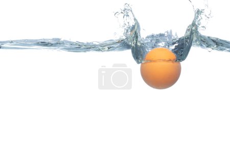Foto de La pelota de ping pong cae en el agua y crea burbujas de aire en la superficie. PingPong Tenis de mesa gota de bola naranja golpeó smash para limpiar el agua y profundo para burbuja. Fondo blanco aislado movimiento de congelación - Imagen libre de derechos