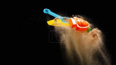 Photo for Sand beach plastic Toy for kid to play along ocean sea beach is red blue yellow green. Digging Molding toy fly with sand in air, Kid enjoy playing colorful toy. Black background isolated - Royalty Free Image