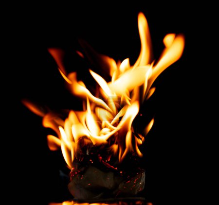 Foto de Llamas de fuego El fuego arde sobre un fondo negro aislado. Encendiendo llamas sobre la textura abstracta del papel. Fuego quemar en papel a las cenizas y crear llama. Foto real de alta resolución - Imagen libre de derechos