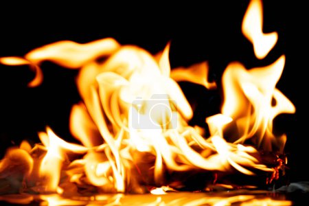 Foto de Llamas de fuego El fuego arde sobre un fondo negro aislado. Encendiendo llamas sobre la textura abstracta del papel. Fuego quemar en papel a las cenizas y crear llama. Foto real de alta resolución borrosa fuera de foco - Imagen libre de derechos