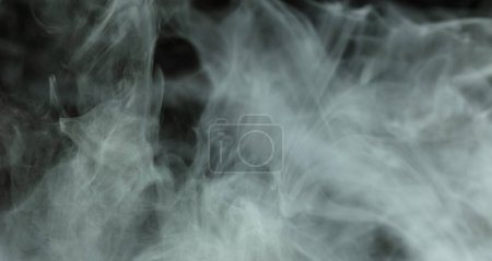 Foto de Densa esponja esponjosa de humo blanco y niebla sobre fondo negro, nubes de humo abstracto, movimiento borroso fuera de foco. Fumar golpes de la máquina de hielo seco volar revoloteando en el aire, textura efecto - Imagen libre de derechos