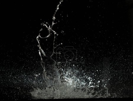 Téléchargez les photos : Jeter des éclaboussures d'eau dans l'attaque de goutte d'eau flottant dans le sol du mur et arrêter le mouvement gel coup de feu. Eau éclaboussante pour la texture de l'explosion éléments de ressources graphiques, fond noir isolé - en image libre de droit