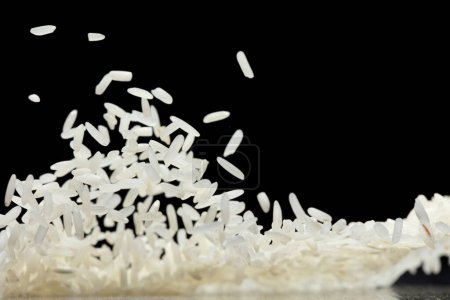 Téléchargez les photos : Riz japonais volant explosion, riz blanc grain rices tomber mouche abstraite. Belle graine complète de riz au jasmin éclaboussure dans l'air, conception d'objets alimentaires. Fond noir isolé foyer sélectif flou - en image libre de droit