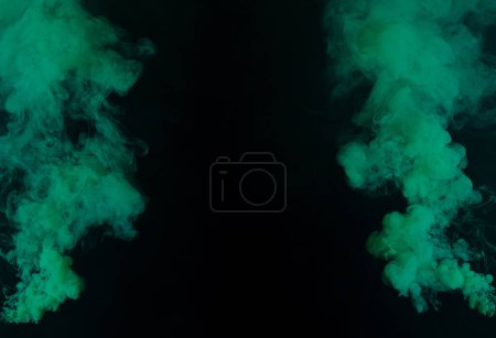 Foto de Green Dense Fluffy Puffs of White Smoke and Fog on black Background, Abstract Smoke Clouds, Movement Blurred out of focus. Fumar golpes de la máquina de hielo seco volar revoloteando en el aire, textura efecto - Imagen libre de derechos