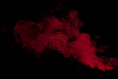 Téléchargez les photos : Bouffées de fumée blanche et de brouillard denses rouges sur fond noir, nuages de fumée abstraits, mouvement flou. Fumeurs soufflant de la machine mouche de glace sèche flottant dans l'air, texture effet - en image libre de droit