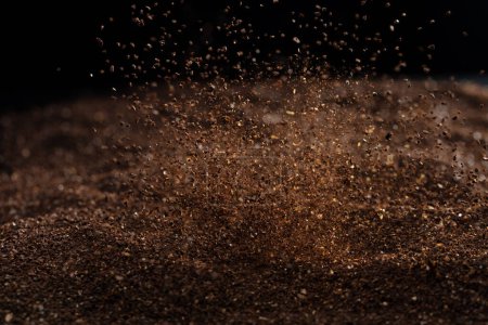 Photo for Ground Coffee roasted powder dust fly explosion, Coffee crushed ground float pouring. Roasted Coffee powder ground dust splash explosion in mid Air. Black background Isolated selective focus blur - Royalty Free Image