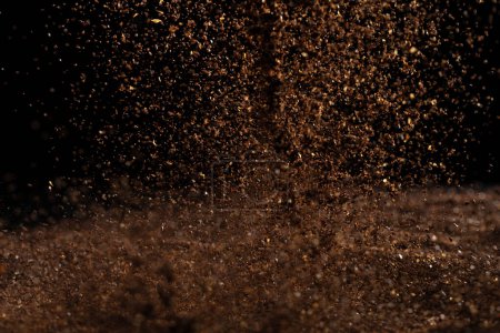 Téléchargez les photos : Ground Coffee roasted powder dust fly explosion, Coffee crushed ground float pouring. Roasted Coffee powder ground dust splash explosion in mid Air. Black background Isolated selective focus blur - en image libre de droit