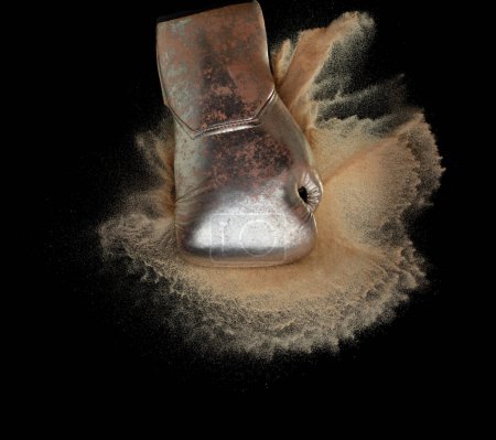 Photo for Boxing glove hit sand and explode. Gold Boxer glove impact sand splash as exercise training. Black background isolated - Royalty Free Image