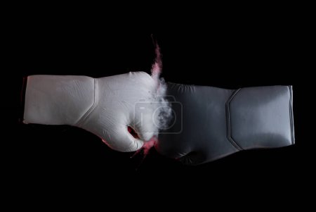 Photo for Two boxing glove in White and Grey face sport confrontation and hit together. Boxing gloves hit together and dust smoke explosion. Black background isolated - Royalty Free Image