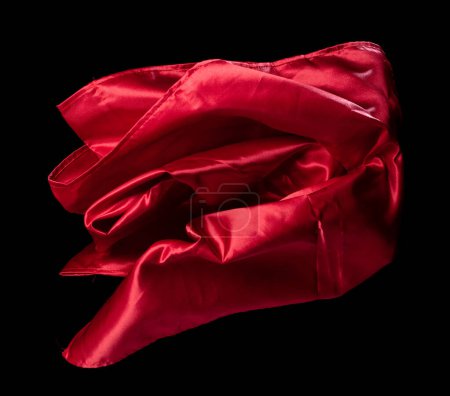 Téléchargez les photos : Tissu satin rouge volant en courbe, morceau de tissu satin rouge textile jeter tomber dans l'air. Fond noir flou de mouvement isolé - en image libre de droit
