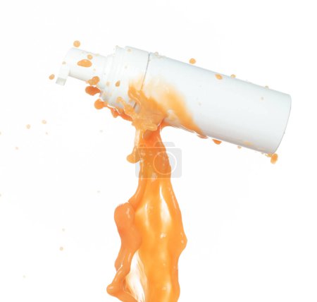 Téléchargez les photos : Crème hydratante au jus d'orange coulant dans un récipient cosmétique. lotion beauté peinture orange flottante explosion dans l'air, éclaboussure comme une gouttelette d'explosion. Fond blanc isolé - en image libre de droit
