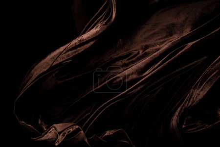 Photo for Brown velvet felt fabric flying in curve shape, Piece of textile Brown velvet felt fabric throw fall in air. Black background isolated, dark shading environment - Royalty Free Image