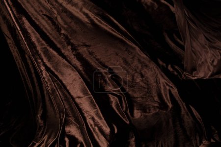 Téléchargez les photos : Tissu en feutre de velours brun volant en forme de courbe, morceau de tissu Tissu en feutre de velours brun jeter tomber dans l'air. Fond noir isolé, ombre foncée - en image libre de droit