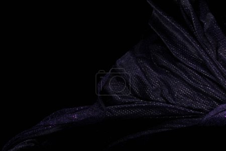 Foto de Tejido violeta púrpura brillo volando en forma de curva, pedazo de tela púrpura tela violeta brillo lanzar caída en el aire. Fondo negro aislado, entorno de sombra oscura - Imagen libre de derechos