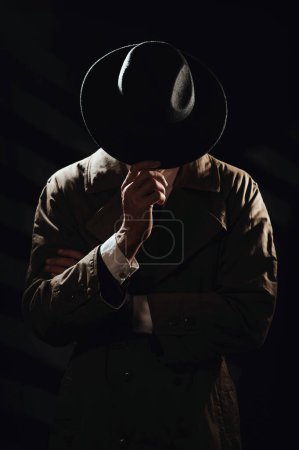 Foto de Una silueta oscura de un hombre de la cara con un abrigo y un sombrero. Un retrato dramático al estilo de las películas de detectives y libros de espionaje de las décadas de 1950 y 1960 - Imagen libre de derechos