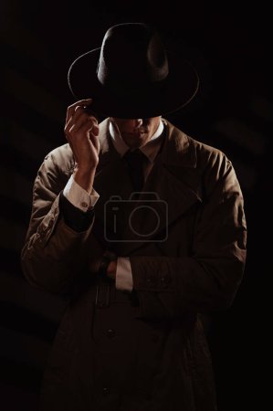Foto de Una silueta oscura de un hombre de la cara con un abrigo y un sombrero. Un retrato dramático al estilo de las películas de detectives y libros de espionaje de las décadas de 1950 y 1960 - Imagen libre de derechos
