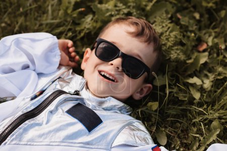 Ein kleiner Junge im Astronautenkostüm spielt draußen auf einem Feld an einem sonnigen Tag.
