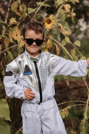 Ein kleiner Junge im Astronautenkostüm spielt an einem sonnigen Tag draußen. Vertikales Foto