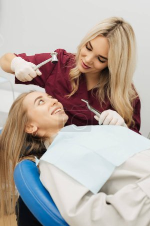 The dentist uses surgical pliers and a hammer to remove a decaying tooth. vertical photo