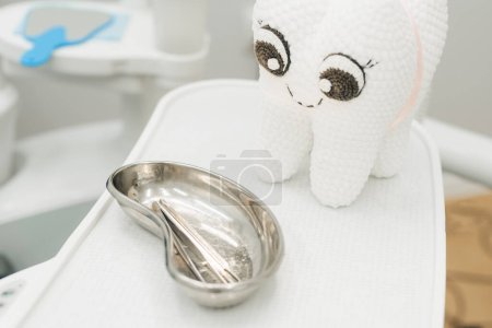 Téléchargez les photos : Une dent en peluche, un miroir et des outils dentaires dans le cabinet du dentiste - en image libre de droit