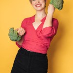 In the studio shot, a young Caucasian woman holds fresh broccoli in her hands. of the healthy eating concept