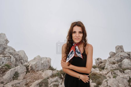 A young fearless woman poses after crossing a rope bridge over a precipice high in the mountains