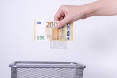 Téléchargez les photos : La main jette deux cents euros dans la poubelle. Le concept de dévaluation de l'euro. - en image libre de droit