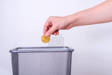Téléchargez les photos : Main sortir Bitcoin dans un conteneur à ordures, Concept de recyclage mondial des ordures et la récession, l'inflation - en image libre de droit