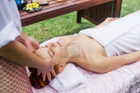 Photo for Young beautiful woman relaxing in spa massage outside in tropical garden. - Royalty Free Image