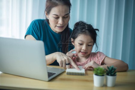 Foto de Feliz madre ayudando a su linda hija a estudiar en línea en casa. Padre e hijo viendo lecciones de arte juntos en el portátil - Imagen libre de derechos
