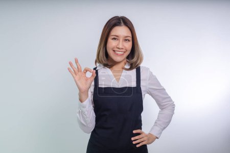Foto de Asiática mujer de negocios mostrando OK gesto contra gris fondo. - Imagen libre de derechos