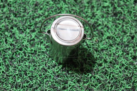 Téléchargez les photos : Petite Handi ronde en aluminium isolée sur une surface verte - en image libre de droit