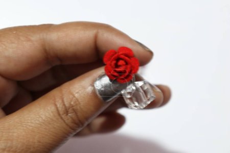 Photo for Hand holding earrings with red flowers and transparent stones - Royalty Free Image