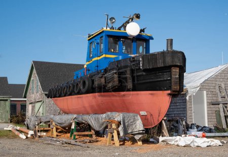 Foto de Antiguo remolcador en reparación: Un remolcador bien conservado espera una restauración adicional en un astillero de Nueva Inglaterra. - Imagen libre de derechos