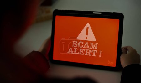 Scam warning screen on tablet screen while using. Concept of security in use of Internet network.