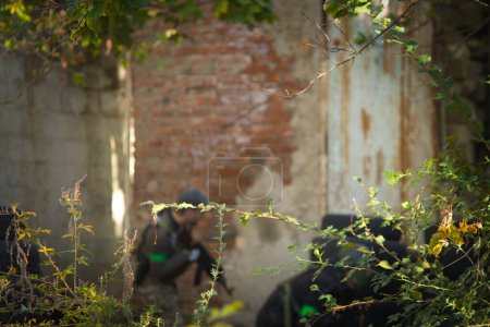 Photo for Silhouette of a man with a gun in the background of green branches and old buildings - Royalty Free Image