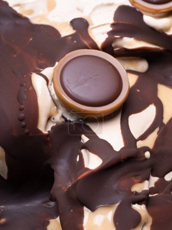 Frozen Toffifee flavour gelato - Vollständiges Rahmendetail. Nahaufnahme von beige cremiger Oberflächentextur von Eis mit Karamell und Schokoladenbelag mit Bonbons.