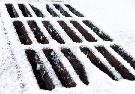 Foto de Rejilla de drenaje de metal cubierta de nieve en invierno. - Imagen libre de derechos