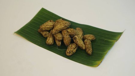 Foto de Kacang rebus, merienda tradicional indonesia, maní al vapor de primer plano servido en hoja de plátano. comúnmente se vende por calle, aislado blanco - Imagen libre de derechos