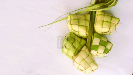 Ketupat-Beutel auf weißem Hintergrund - Ketupat ist eine Art Knödel aus Reis, verpackt in einem diamantförmigen Behälter aus geflochtenem Palmblattbeutel, traditionelles muslimisches Essen während der Feier des Eid al-Fitr