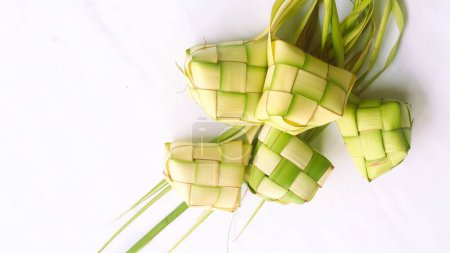 Ketupat-Beutel auf weißem Hintergrund - Ketupat ist eine Art Knödel aus Reis, verpackt in einem diamantförmigen Behälter aus geflochtenem Palmblattbeutel, traditionelles muslimisches Essen während der Feier des Eid al-Fitr