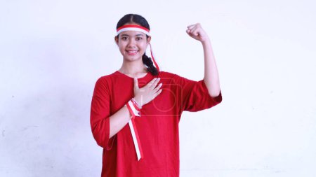 Excited Asian girl wearing red shirt and red white ribbon on her head during Indonesia independence day celebration, isolated white, copy space