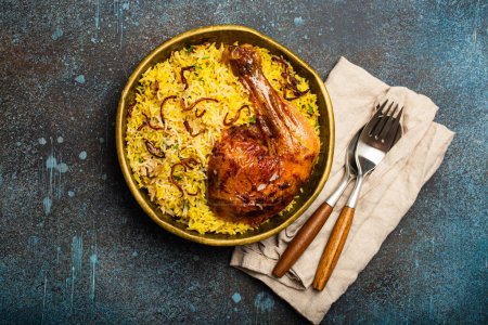 Téléchargez les photos : Délicieux plat indien Biryani cuisse de poulet avec riz basmati dans un vieux bol en laiton métallique sur fond de pierre rustique de table. Nourriture traditionnelle non végétarienne de l'Inde - en image libre de droit