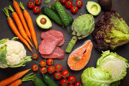 Photo for Assorted food raw products: vegetables, beef meat steak, fish salmon fillet on dark rustic brown stone table top view. Healthy food background, ingredients with vitamins concept, diet and nutrition - Royalty Free Image