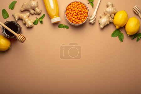 Photo for Lemons, mint, ginger, sea buckthorn berries, honey in glass jar, orange drink in bottle top view. Food for immunity stimulation and against flu. Healthy remedies to boost immune system, copy space. - Royalty Free Image