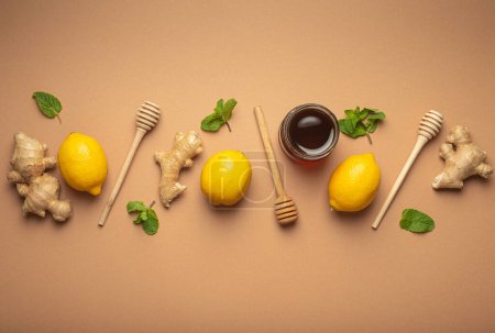 Photo for Composition with lemons, mint, ginger, honey in glass jar and honey wooden dippers top view. Food for immunity stimulation and against seasonal flu. Healthy natural remedies to boost immune system. - Royalty Free Image