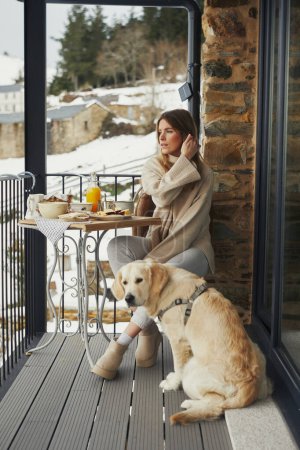 Femme avec chien bénéficiant d'une vue sur le balcon enneigé.
