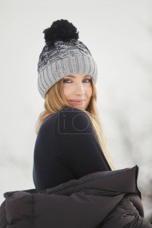 Portrait of a woman in winter wear with a snowy background.